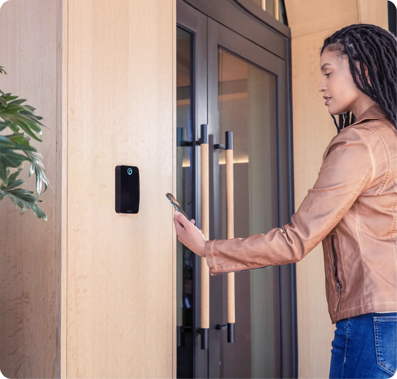Woman in a brown jacket using her phone to unlock a smart door lock on a wooden door.
