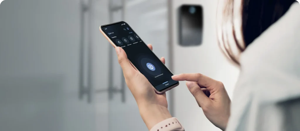 Hands hold a smartphone with a voice assistant interface and circular mic button on screen, ready to speak.
