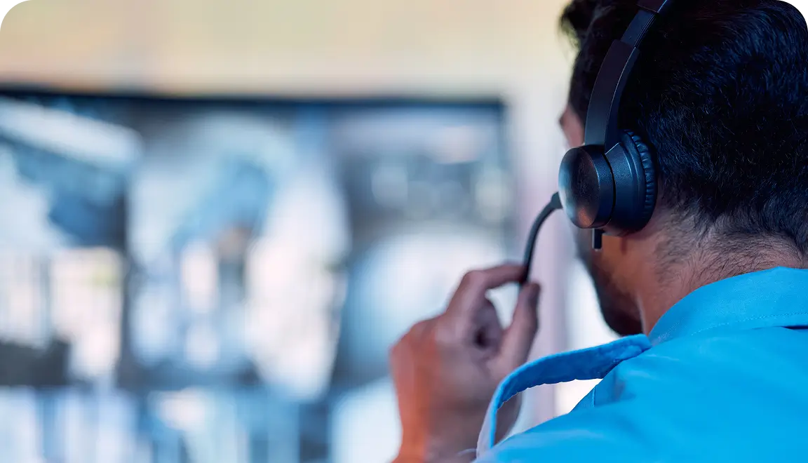 Person wearing a headset at a computer, focused on a blurred monitor in the background, likely a support agent